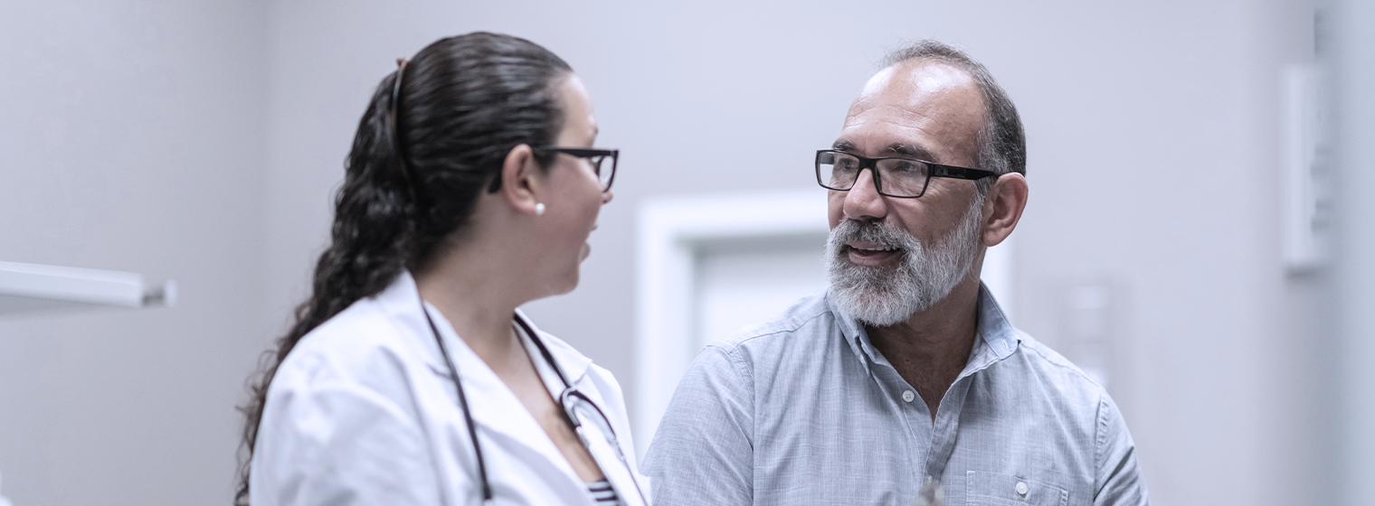 Female primary care provider talks to middle 年龄d male patient.