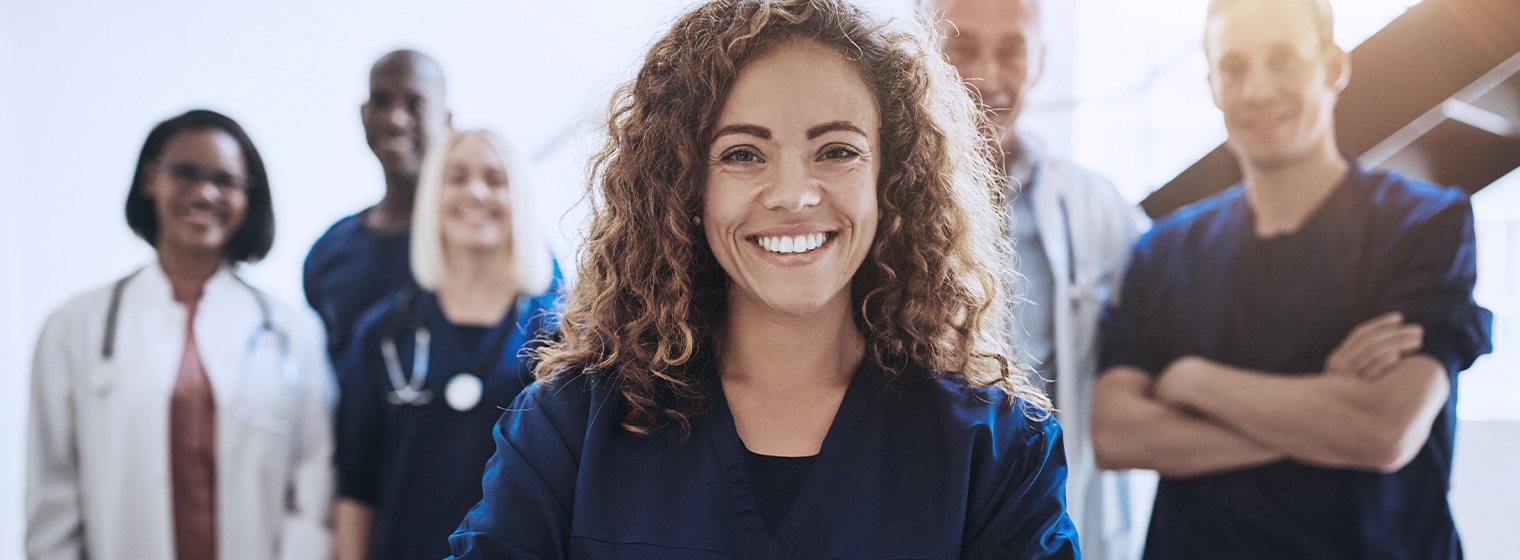 young female nurse smiling with other medical staff behind her