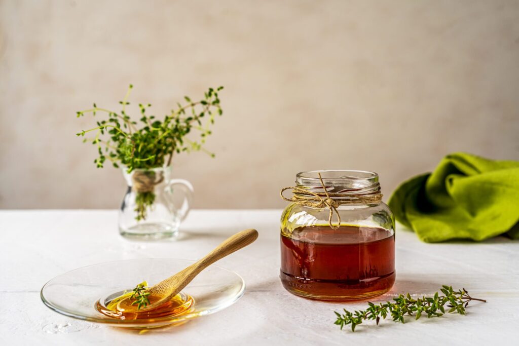 Jar-of-honey-on-table-with-spoon-and-plate-nearby-as-example-of-Appalachian-home-remedies