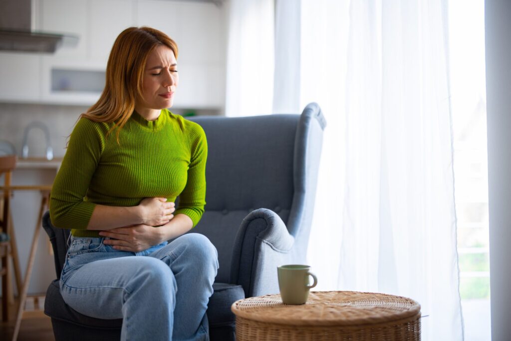Woman-with-stomach-ache-sitting-in-char