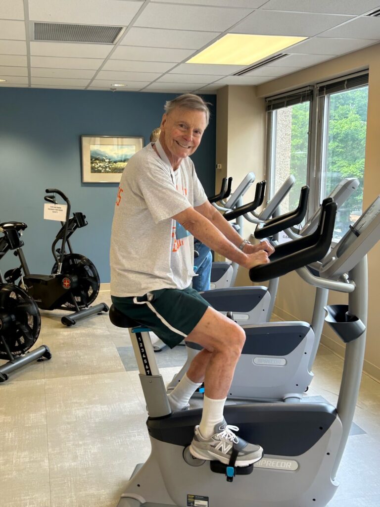Jay on stationary bicycle smiling.