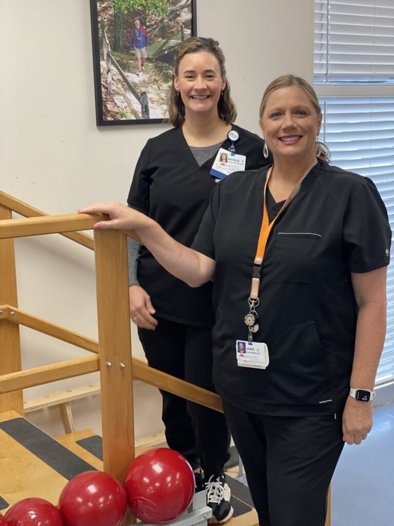 Two therapists dressed in black, standing by therapy stairs.