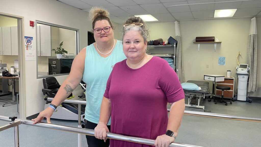 Mother and daughter in colorful shirts, standing in PT gym.