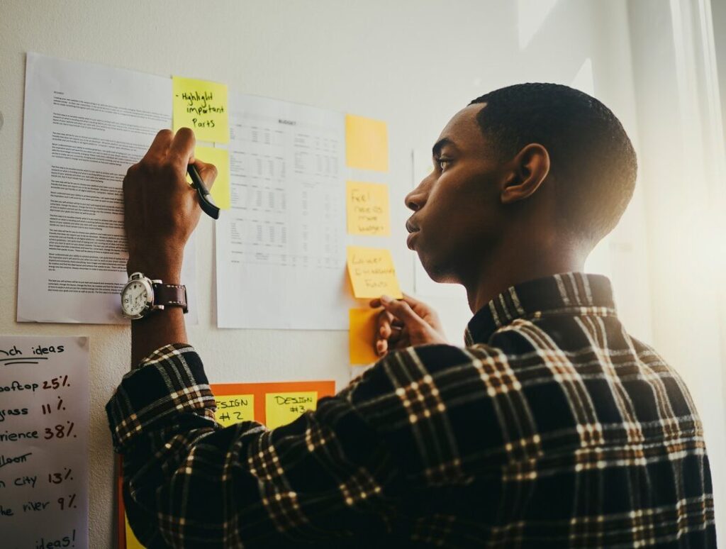 Man organizing tasks by posting lists on wall