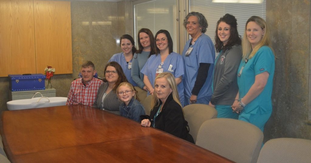 Featured image Danielle Rouse and her family sit at a table surrounded by staff from the women's services unit