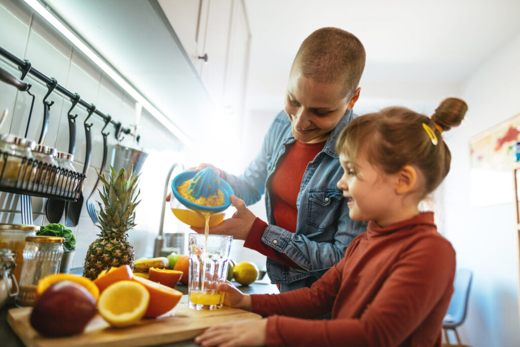 mom with cancer makes orange juice in kitchen health nutrition daughter