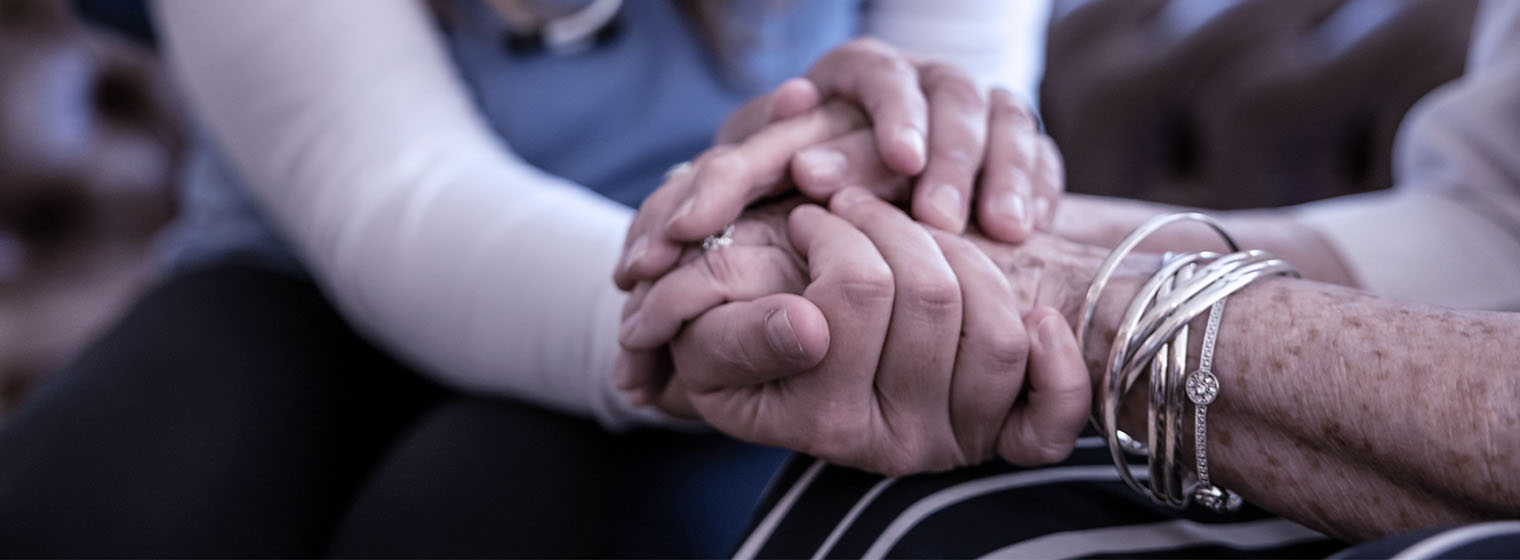close up view of behavioral health nurse and senior holding hands
