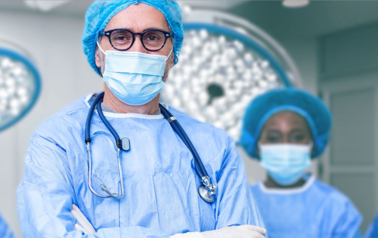 Surgeons in scrubs and mask looking directly at camera