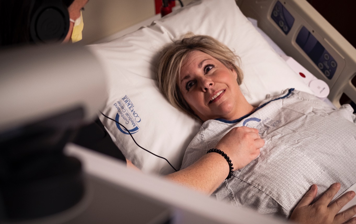 female patient laying in hospital bed looking at doctor