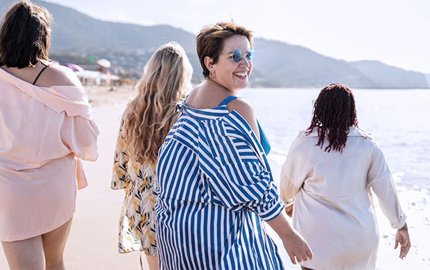 four people walking down beach smiling