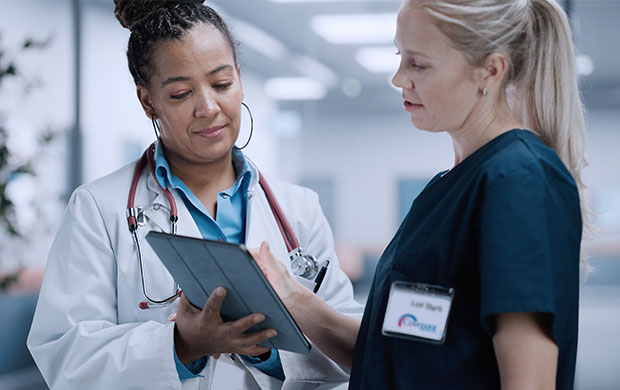 doctor in white coat shows tablet computer screen to covenant health nurse