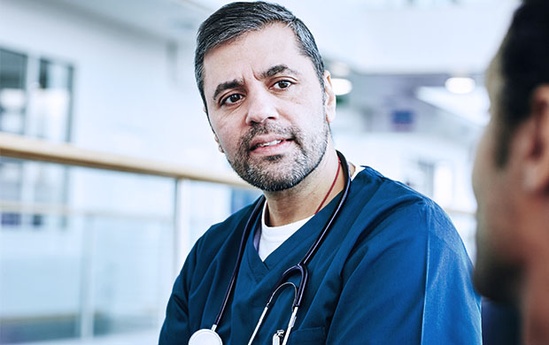 middle-aged male nurse with stethoscope looks at man standing beside him