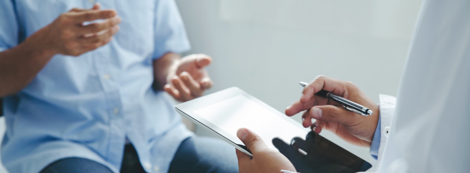 patient gesturing with hands to doctor holding a clipboard