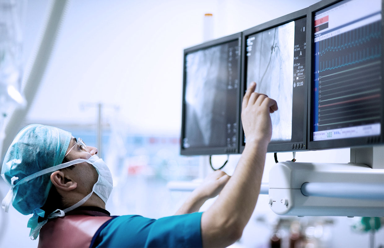 surgeon in scrubs looks at scan on screen