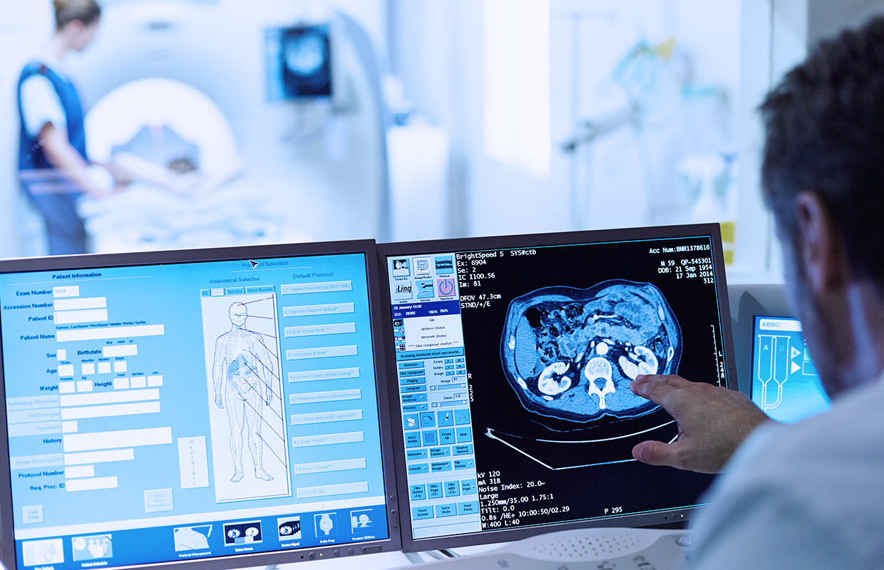 Physician looks at CT scan on computer monitor.