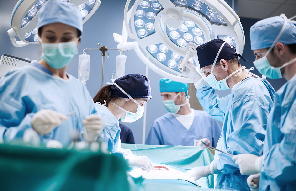 group of five surgeons performing a procedure in operating room