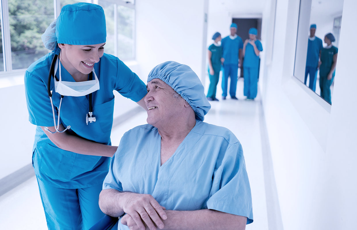 young female nurse in scrubs talking to male patient in scrubs in a wheelchair