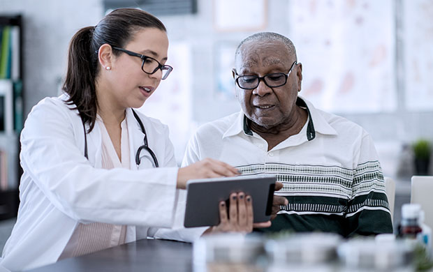female doctor shows older man his test results on a tablet