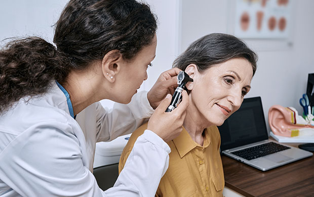 young female doctor examines ear of middle age female patient