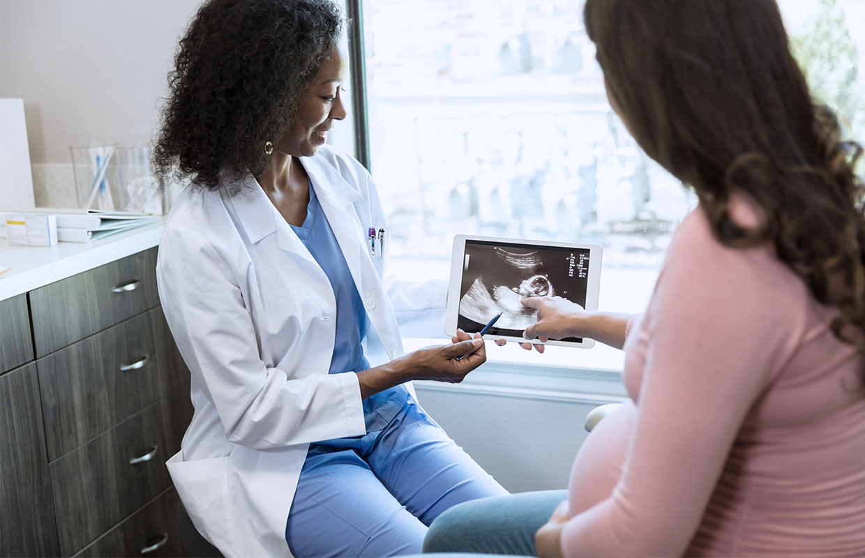 a doctor shows a pregnant mom results from an ultrasound