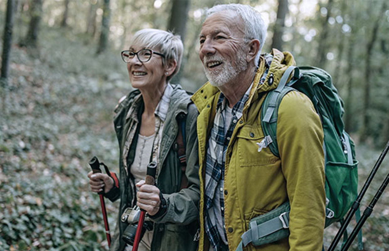 senior female and senior male hiking through the woods