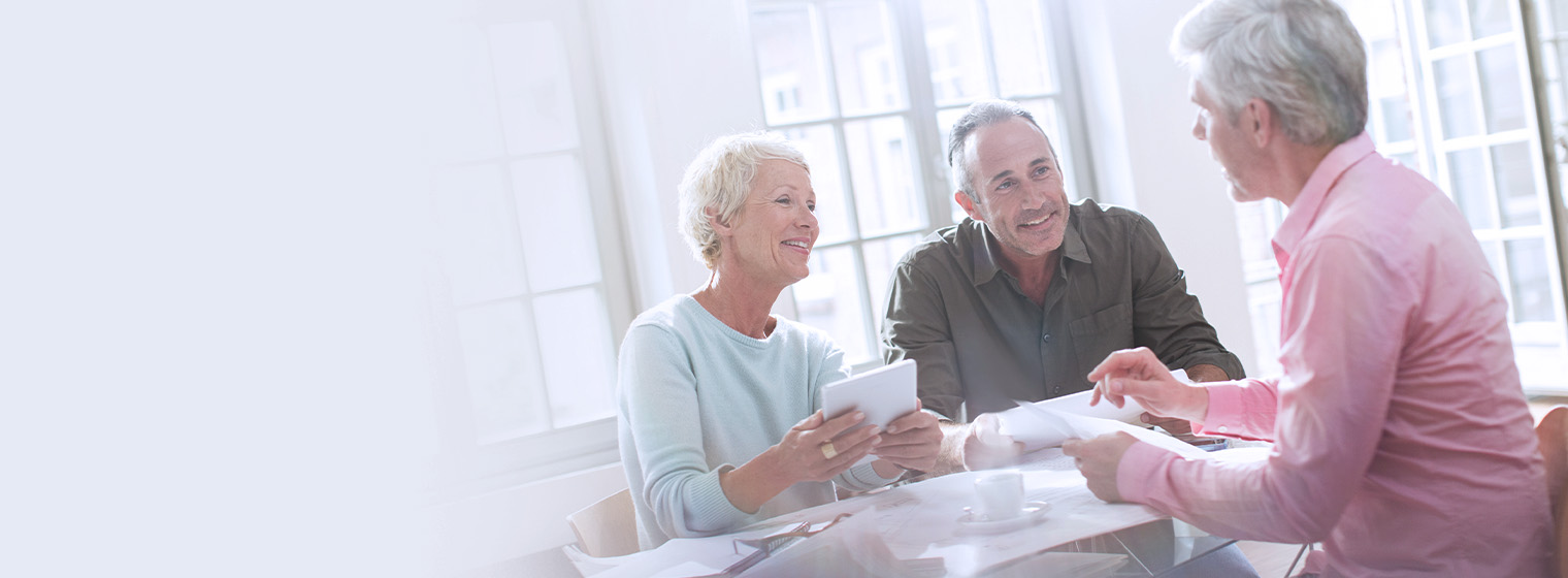 elderly couple talking to a senior male in an office