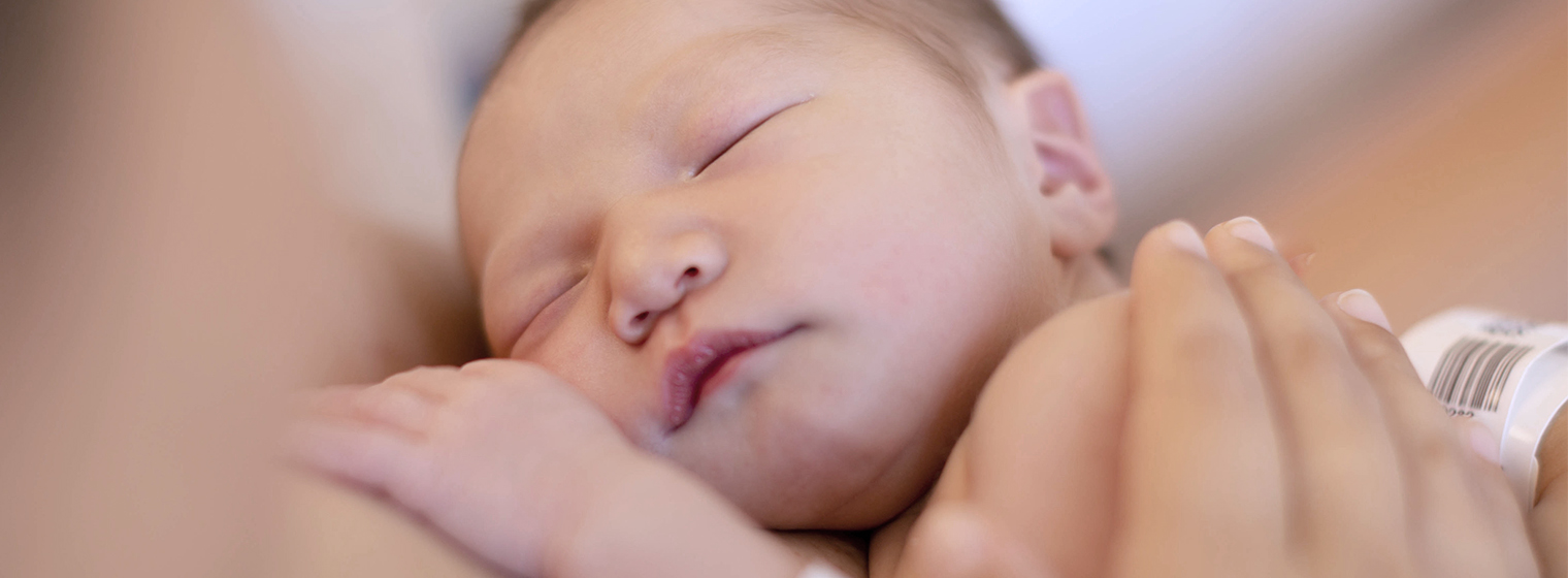 close up image of a newborn baby held by a mom