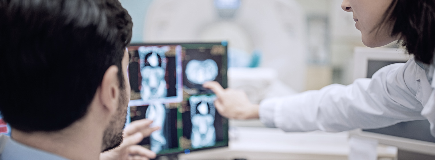 Two doctors examine a cancer patient's scan to discuss treatment options.