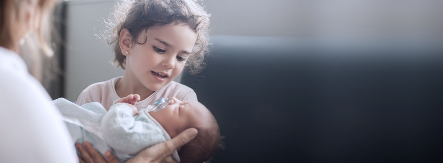 toddler girl holding her new sibling