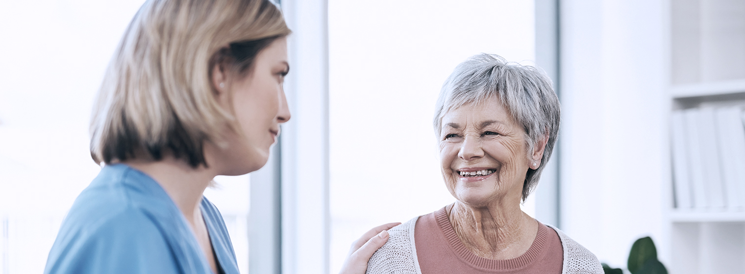 female nurse talking to elderly female patient smiling