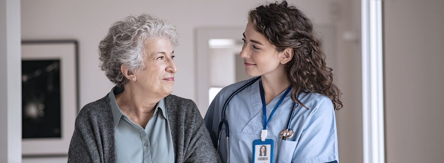 elderly female patient looking at young female nurse smiling