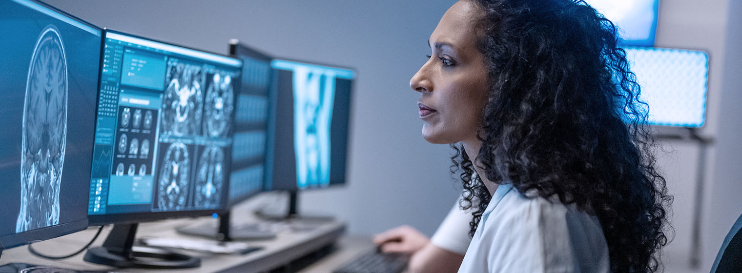 female medical professional looking at images on computer screens