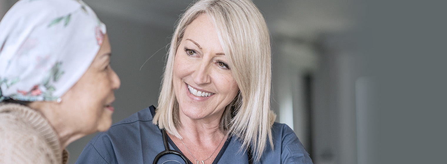 young female nurse smiling at older breast cancer patient