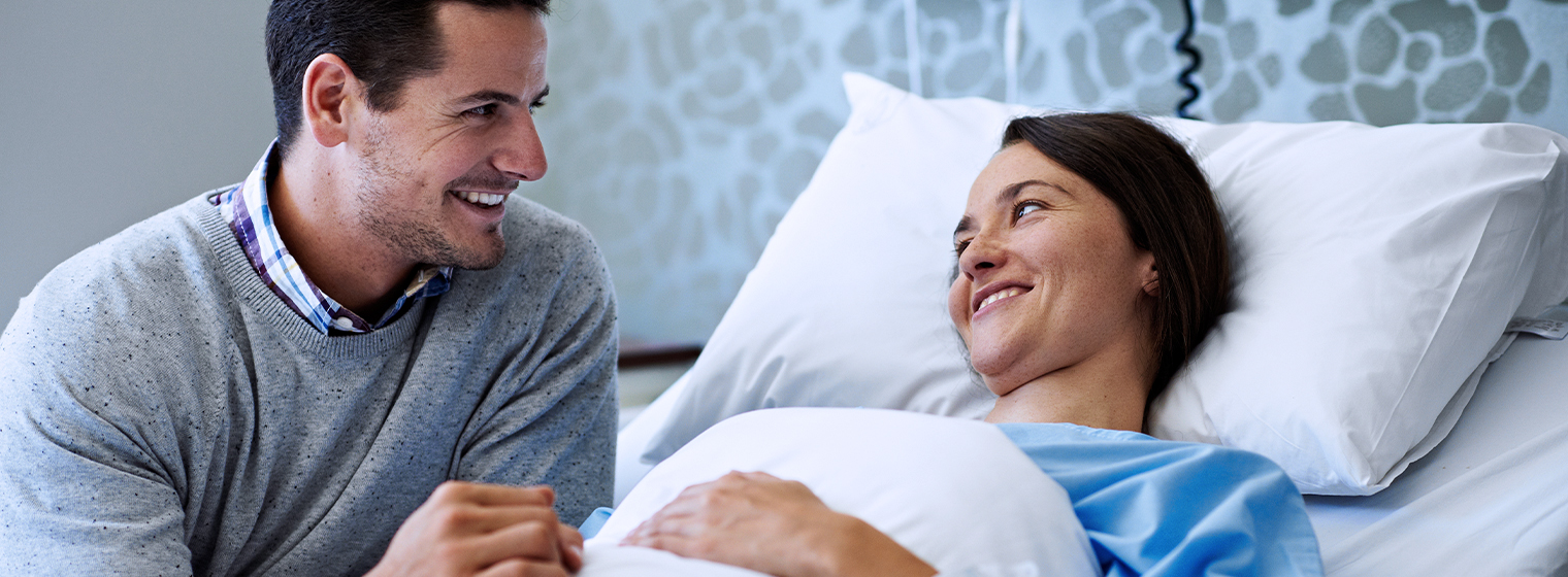 middle age male chaplain with a middle age female patient in a hospital bed