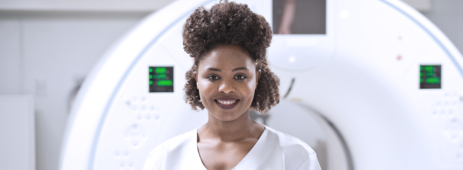 young female doctor smiling in front of an imaging machine