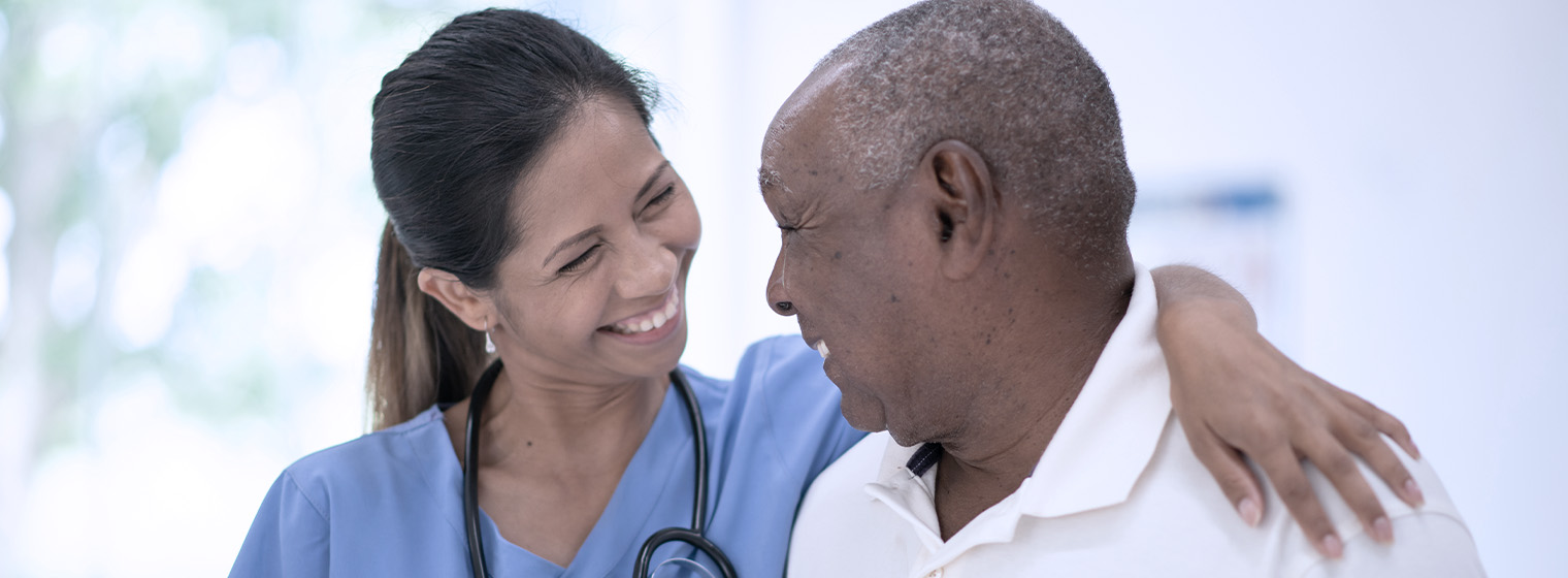 young female nurse with arm around elderly male patient