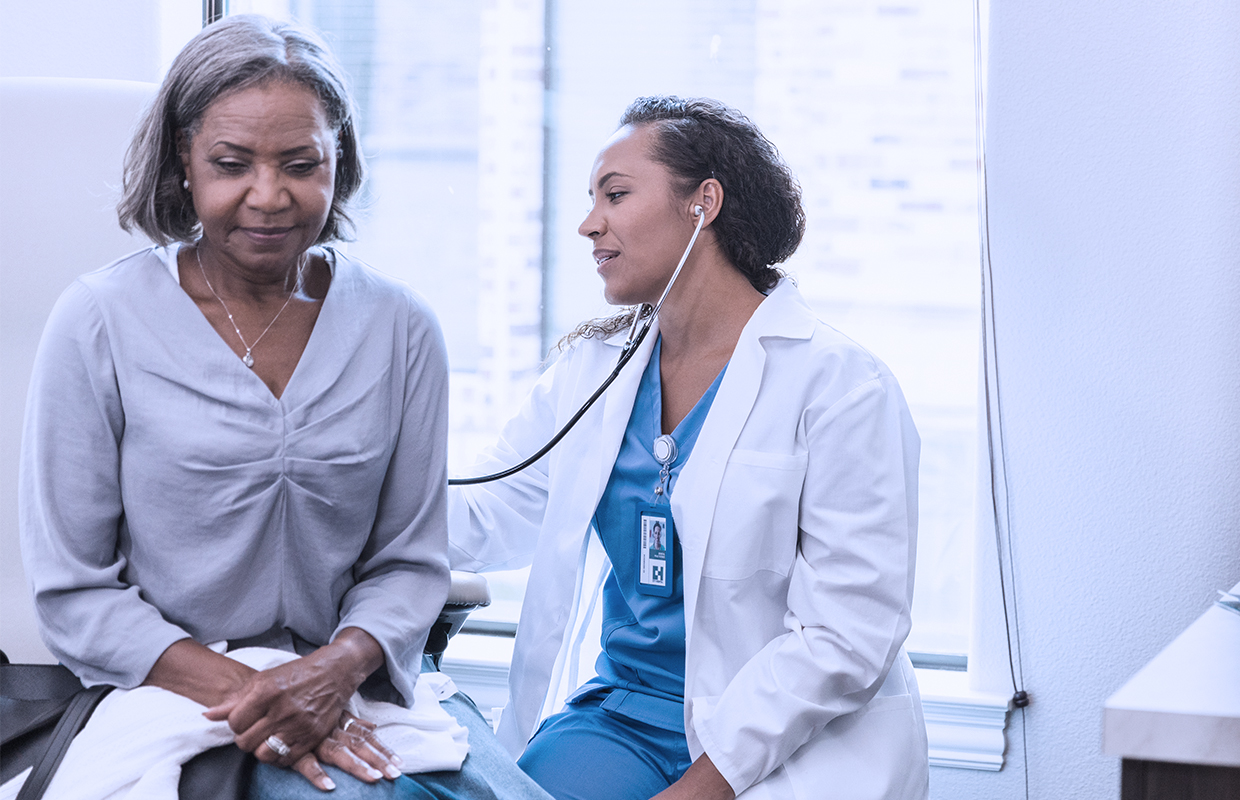 doctor listening to the lungs of a senior female patient