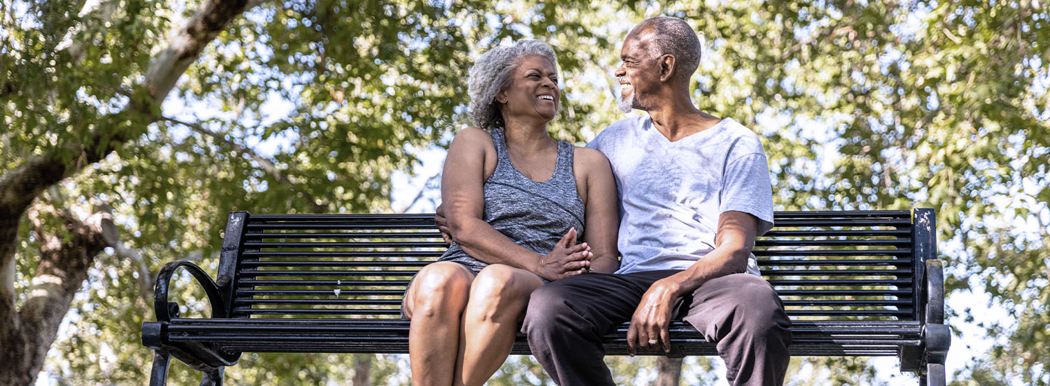 senior female and male sitting on a bench in a park