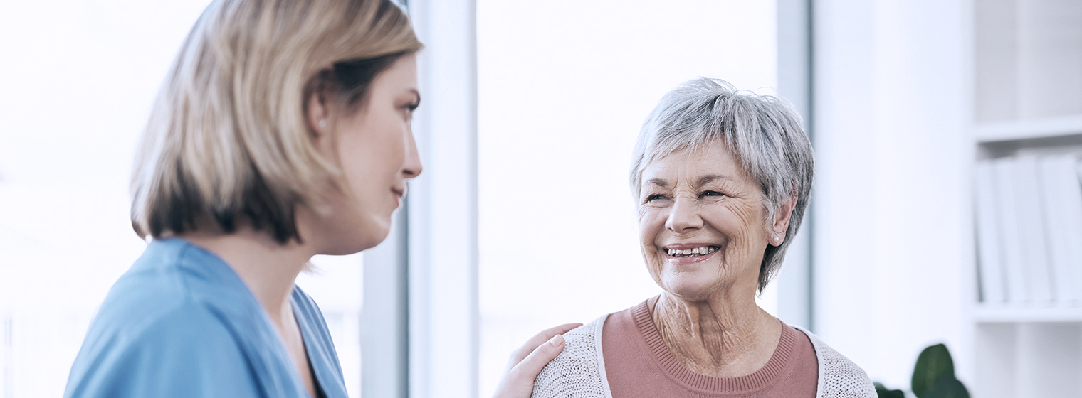 a medical provider touches the shoulder of a smiling elderly lady