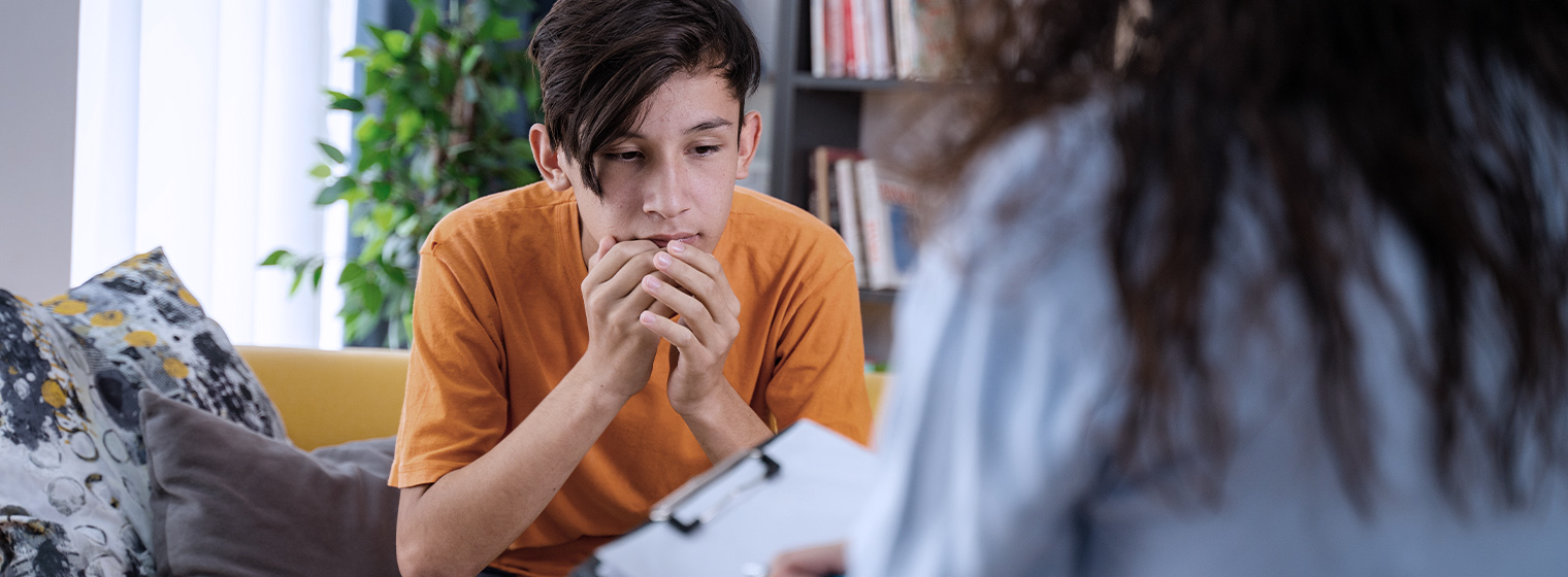 young male biting his nails while talking to a therapist