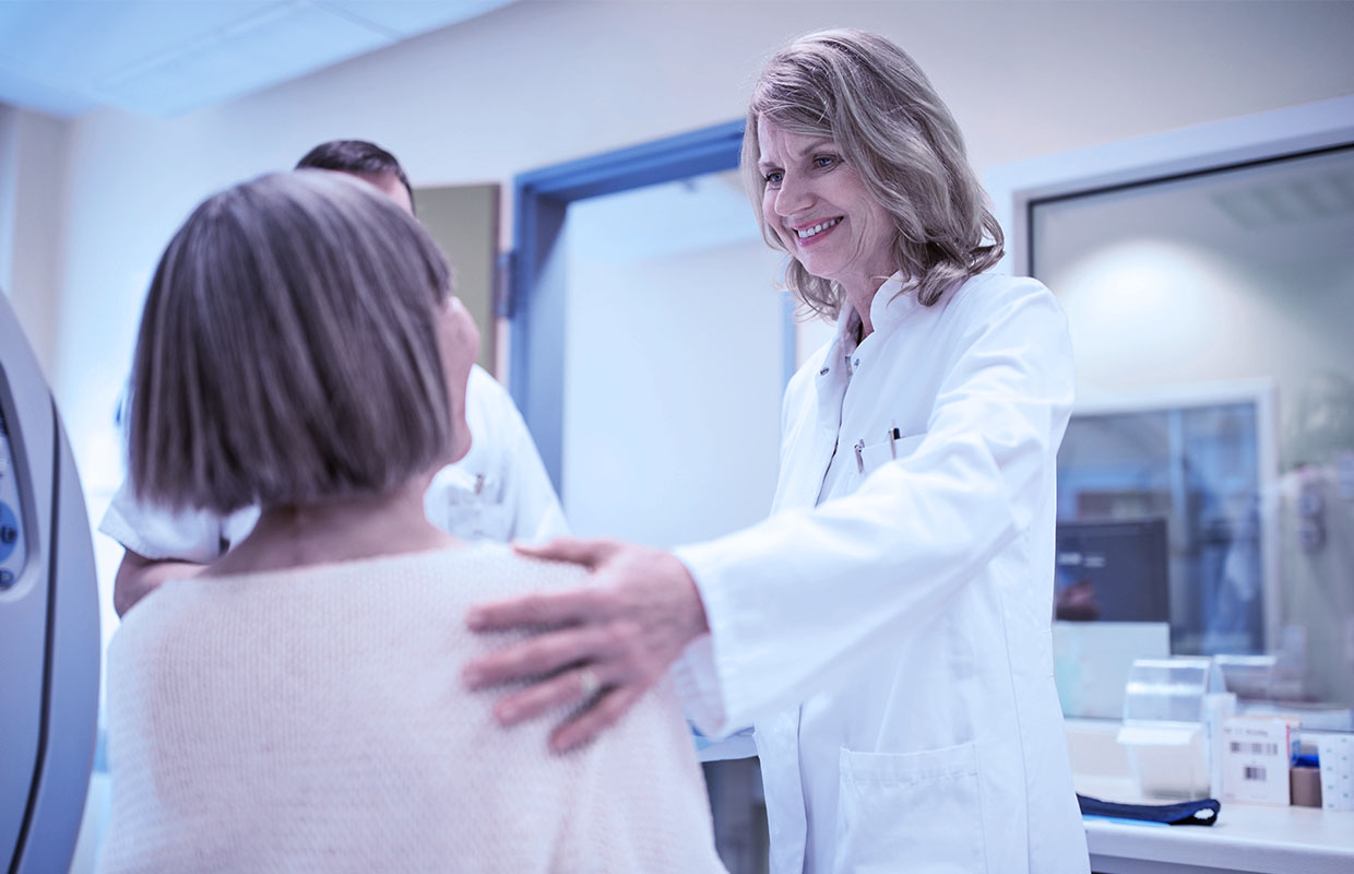 Female doctor comforts cancer patient who just finished a CT scan.