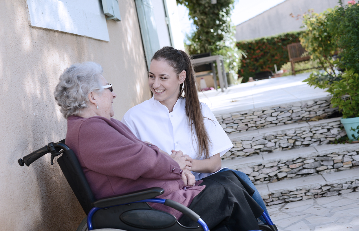 young female sits with elderly female on a bench outside