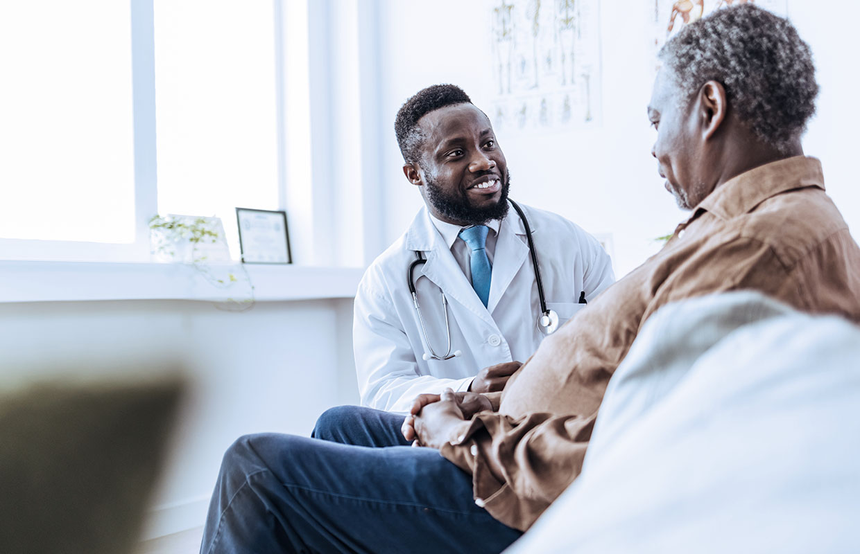a doctor smiles and talks to an elderly patient