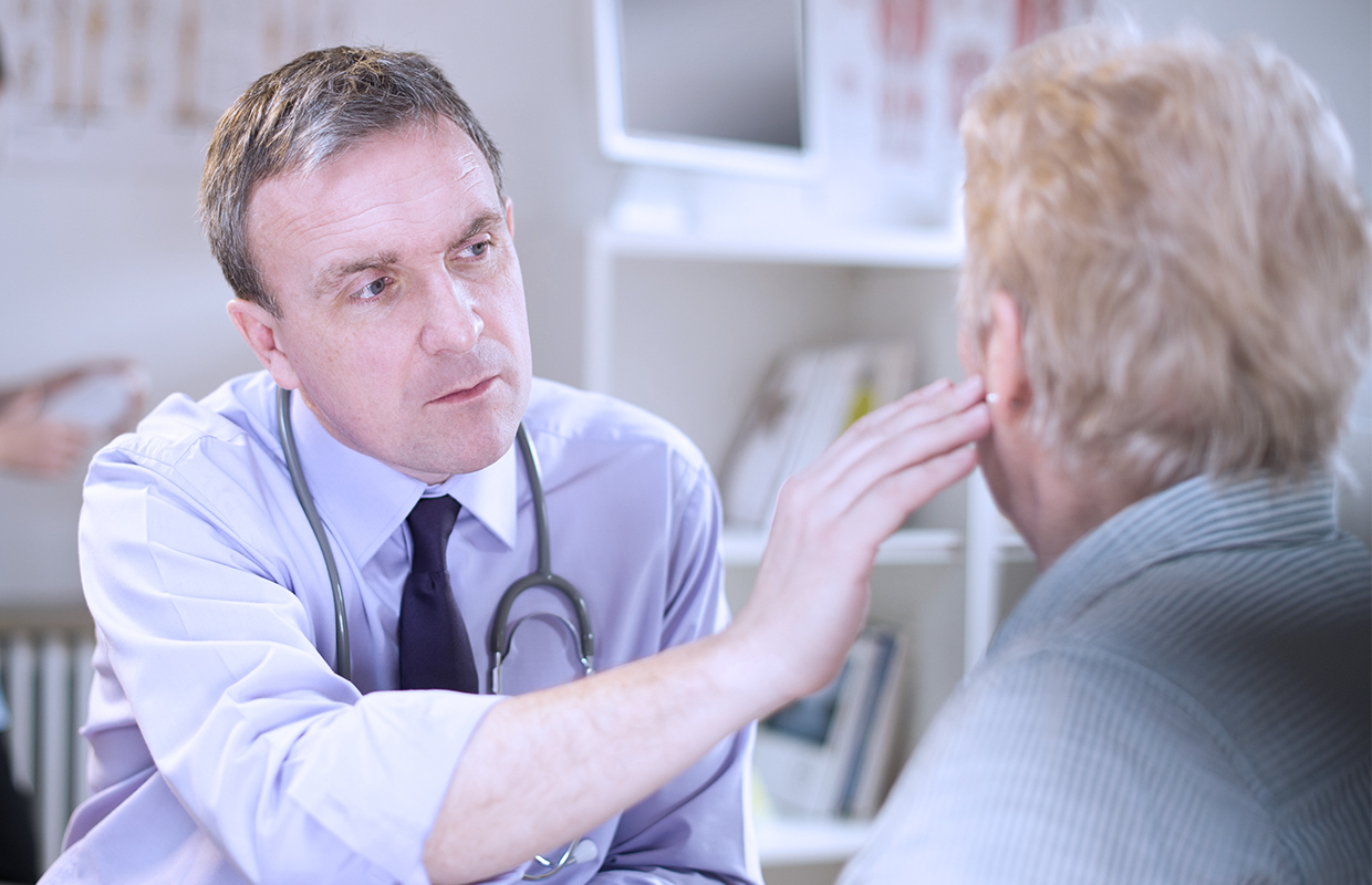 Male doctor examines female patient's ear in exam room