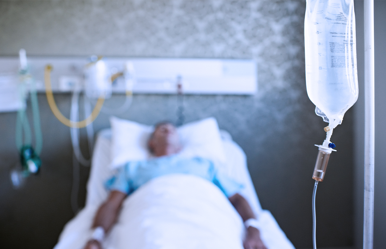 man in hospital bed with IV drip