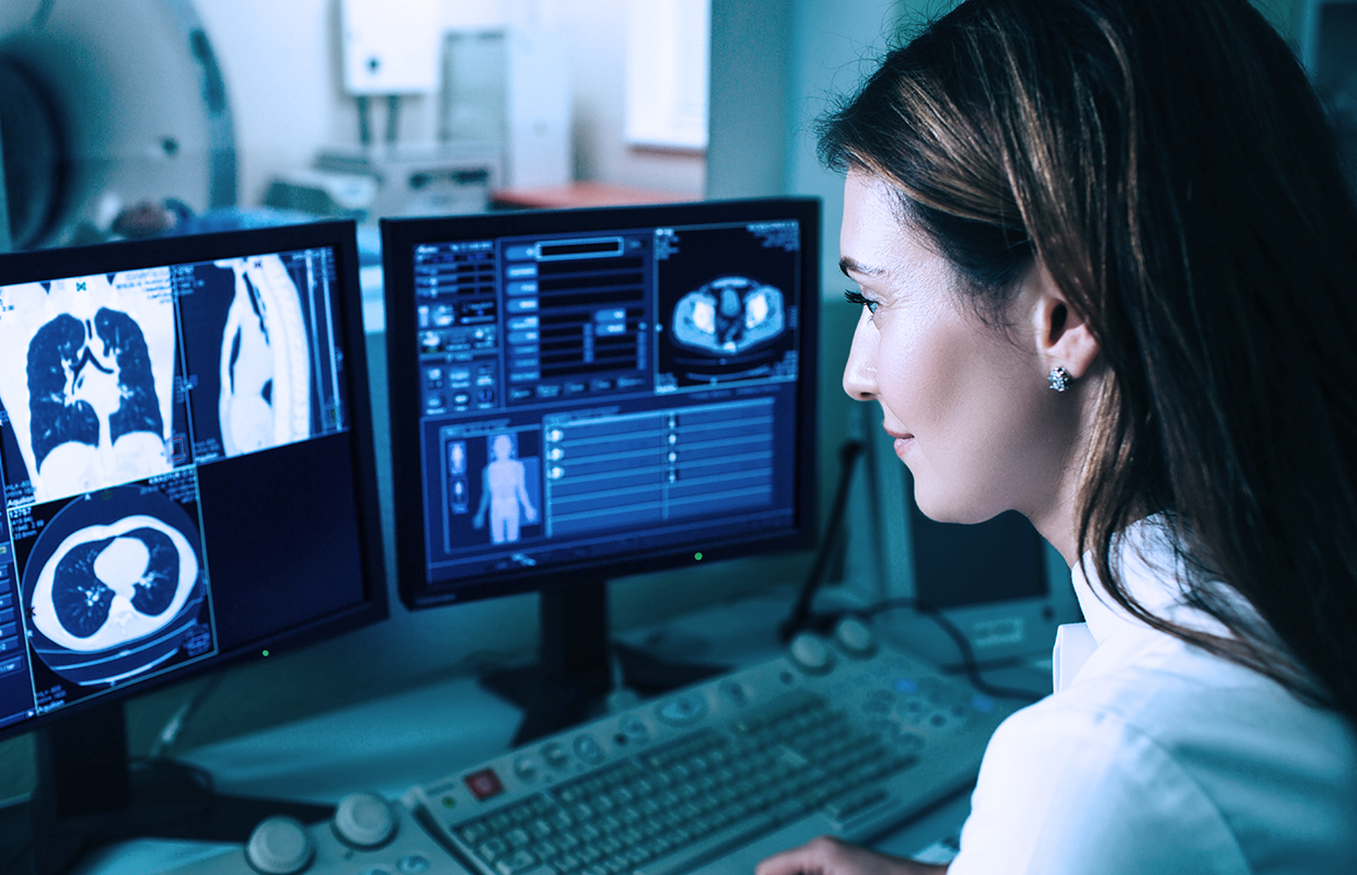 Physician examines CT scan on computer screen.