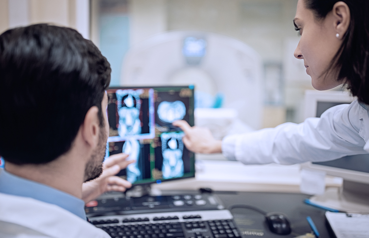 female and male nurse look at scan on computer screen