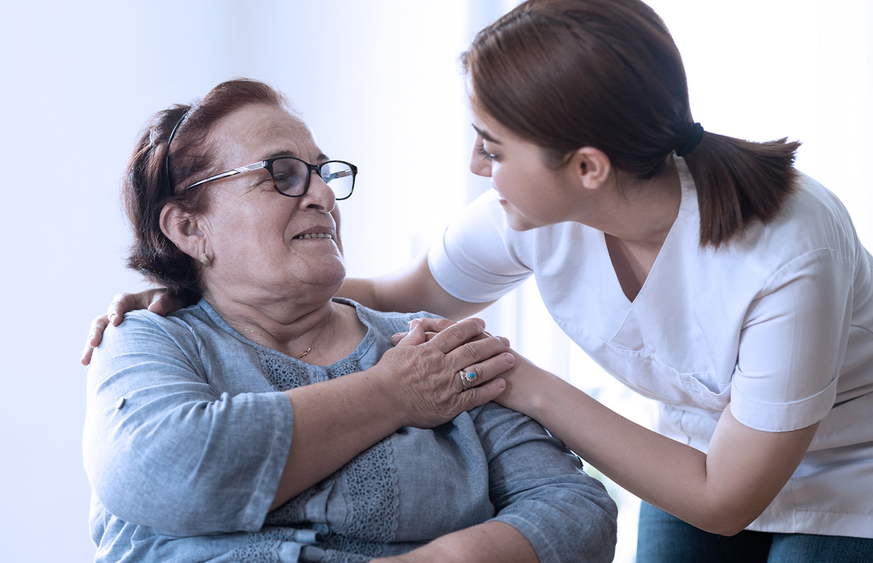 young female helping elderly patient and holding her hand