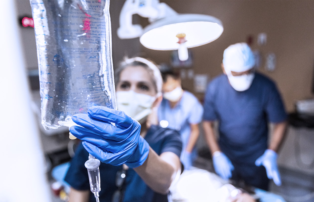 female nurse hangs IV bag in hospital room