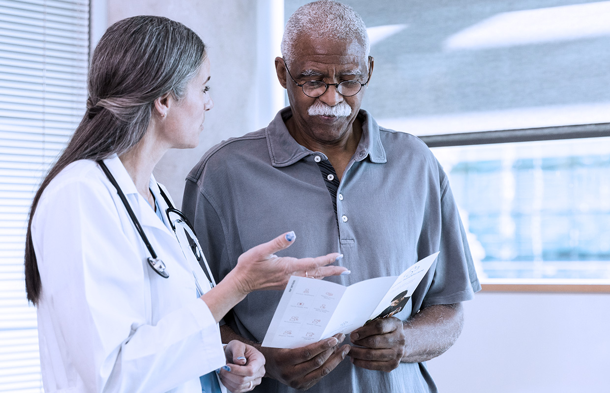 Female cancer doctor speaks to senior male patient.